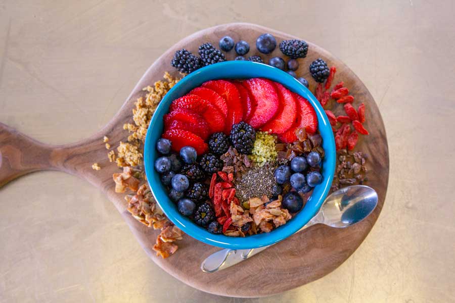 A delicious Acai bowl that includes toppings such as berry assortment, chia, hemp seeds, granola and nuts.